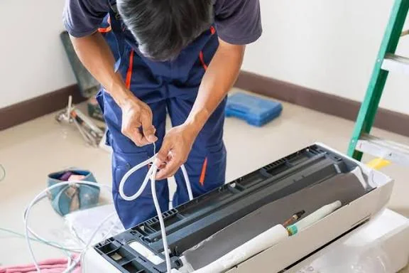 Technician connecting lines during an indoor air conditioning installation